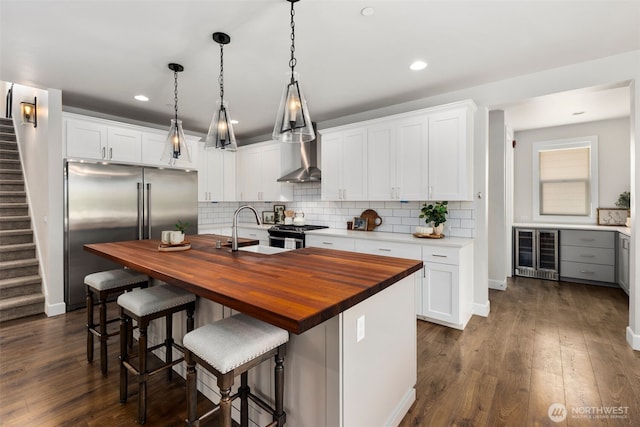 8009 197th Ave E, Bonney Lake, WA 98391 - kitchen with butcher block counters, beverage cooler, appliances with stainless steel finishes, decorative backsplash, and an island with sink