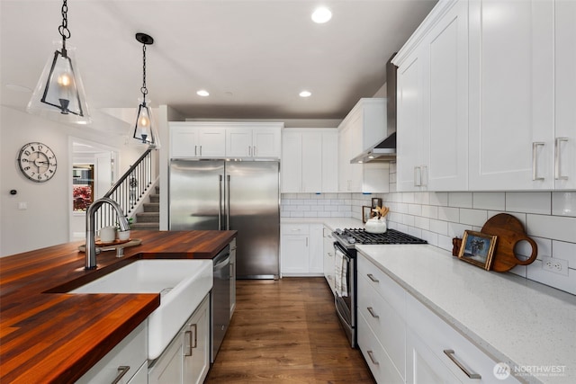 8009 197th Ave E, Bonney Lake, WA 98391 - kitchen featuring wood counters, stainless steel appliances, wall chimney exhaust hood, decorative backsplash, and recessed lighting
