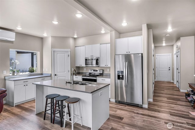 2912 Sandwood Ln, Blaine, WA 98230 - kitchen with stainless steel appliances, a sink, wood finished floors, a kitchen bar, and white cabinetry
