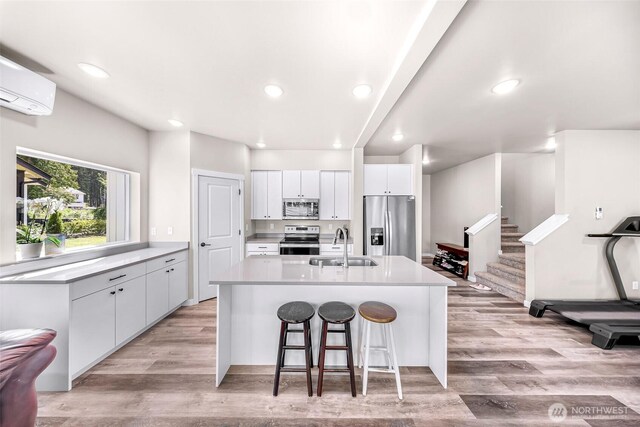 2912 Sandwood Ln, Blaine, WA 98230 - kitchen featuring stainless steel appliances, a sink, light wood-style flooring, a wall mounted air conditioner, and a center island with sink