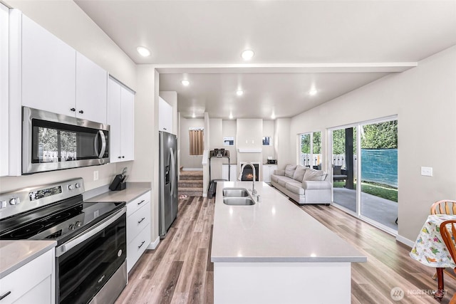 2912 Sandwood Ln, Blaine, WA 98230 - kitchen with stainless steel appliances, a sink, light wood-style floors, light countertops, and a center island with sink