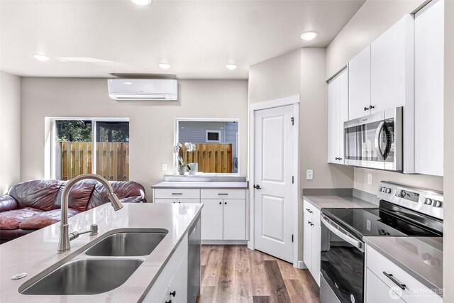 2912 Sandwood Ln, Blaine, WA 98230 - kitchen with stainless steel appliances, a sink, a wall mounted air conditioner, open floor plan, and light wood-type flooring