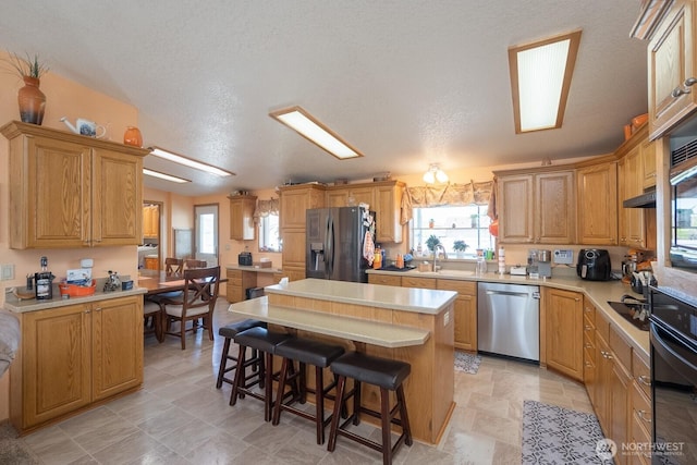307 Hilltop Cir, Ephrata, WA 98823 - kitchen with black appliances, a center island, a kitchen bar, and plenty of natural light