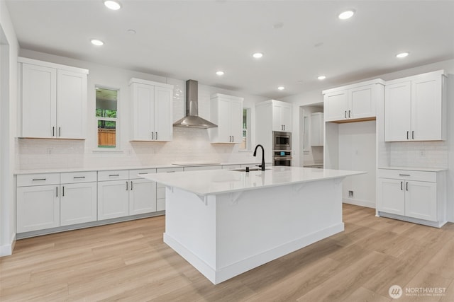 15706 210th Ave E Unit 312, Bonney Lake, WA 98391 - kitchen featuring wall chimney range hood, appliances with stainless steel finishes, light wood-type flooring, tasteful backsplash, and white cabinets