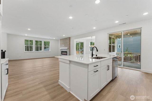 15706 210th Ave E Unit 312, Bonney Lake, WA 98391 - kitchen with a sink, stainless steel dishwasher, light wood finished floors, light countertops, and a large fireplace