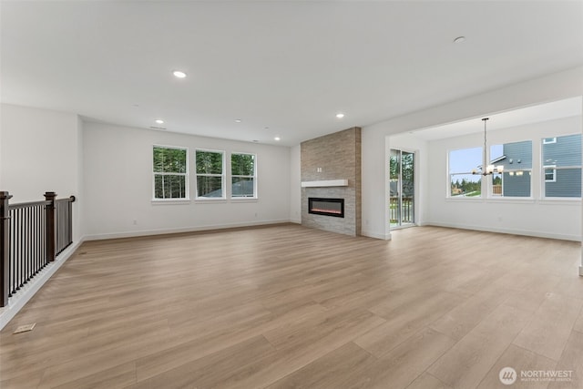 15706 210th Ave E Unit 312, Bonney Lake, WA 98391 - unfurnished living room with a chandelier, plenty of natural light, light wood-style flooring, a large fireplace, and recessed lighting