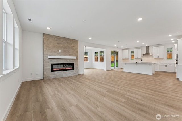 15706 210th Ave E Unit 312, Bonney Lake, WA 98391 - unfurnished living room with light wood-type flooring, a stone fireplace, baseboards, recessed lighting, and a sink