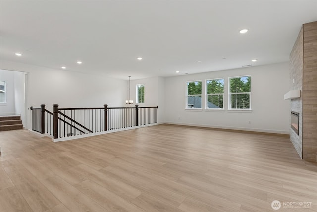 15706 210th Ave E Unit 312, Bonney Lake, WA 98391 - unfurnished living room featuring light wood finished floors, a chandelier, recessed lighting, a large fireplace, and baseboards