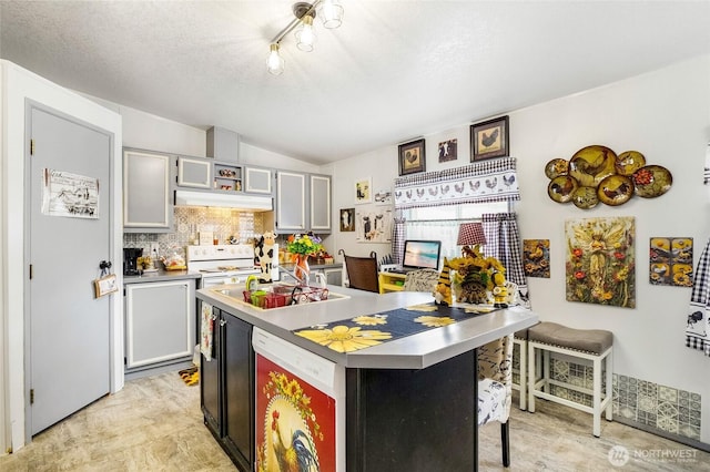 3211 W Wapato Dr Unit 26, Moses Lake, WA 98837 - kitchen featuring vaulted ceiling, decorative backsplash, a breakfast bar area, a textured ceiling, and under cabinet range hood