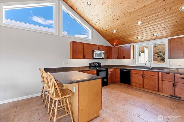 340 W Beach Dr, Orondo, WA 98843 - kitchen featuring black appliances, a sink, a peninsula, a kitchen bar, and light tile patterned floors