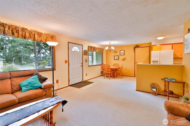 247 Bass Ave NE, Ocean Shores, WA 98569 - living area with a chandelier, plenty of natural light, a textured ceiling, carpet flooring, and baseboards