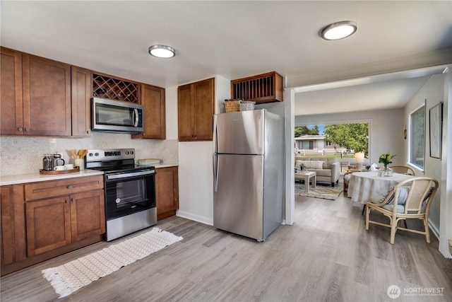 1108 116th St S, Tacoma, WA 98444 - kitchen with appliances with stainless steel finishes, light wood finished floors, light countertops, tasteful backsplash, and brown cabinetry