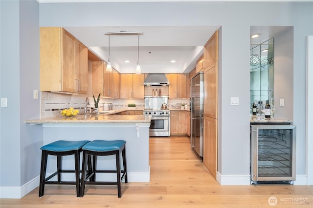 177 107th Ave NE Unit 2401, Bellevue, WA 98004 - kitchen with beverage cooler, high quality appliances, a peninsula, wall chimney exhaust hood, and light wood-style floors