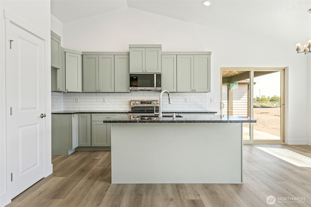 217 N Sandy Loop, Moses Lake, WA 98837 - kitchen featuring stainless steel appliances, tasteful backsplash, dark stone counters, light wood-style flooring, and high vaulted ceiling
