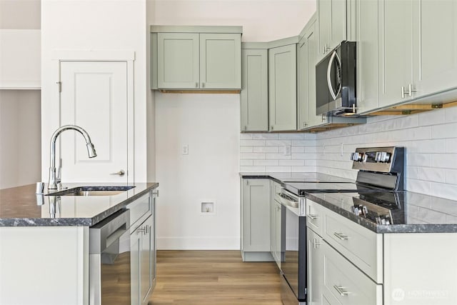 217 N Sandy Loop, Moses Lake, WA 98837 - kitchen with appliances with stainless steel finishes, backsplash, light wood-style floors, dark stone counters, and green cabinetry