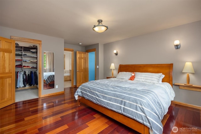 6570 Cedar Glade Ln, Bainbridge Island, WA 98110 - bedroom with wood finished floors, a walk in closet, a closet, baseboards, and connected bathroom