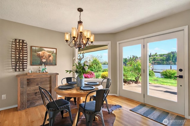293 State Route 409, Cathlamet, WA 98612 - dining space featuring a chandelier, light wood-style flooring, baseboards, a textured ceiling, and a water view