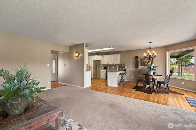 293 State Route 409, Cathlamet, WA 98612 - living room with a chandelier, a textured ceiling, baseboards, light colored carpet, and light wood-type flooring
