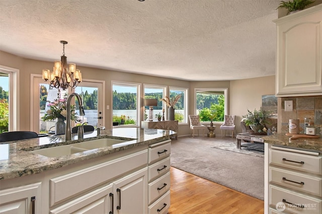293 State Route 409, Cathlamet, WA 98612 - kitchen featuring a sink, a chandelier, a textured ceiling, a water view, and light wood-style floors