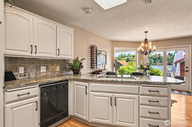 293 State Route 409, Cathlamet, WA 98612 - kitchen with black dishwasher, a sink, light wood-style flooring, a peninsula, and white cabinets