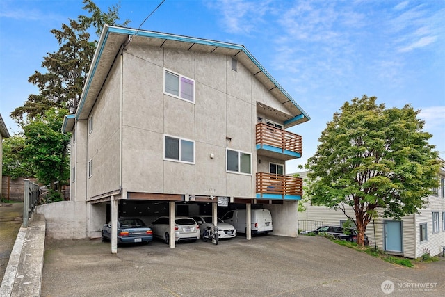 6710 24th Ave NW, Seattle, WA 98117 - rear view of property with a balcony, covered parking, and stucco siding