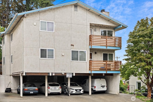 6710 24th Ave NW, Seattle, WA 98117 - back of property with a balcony, stucco siding, a chimney, and covered parking