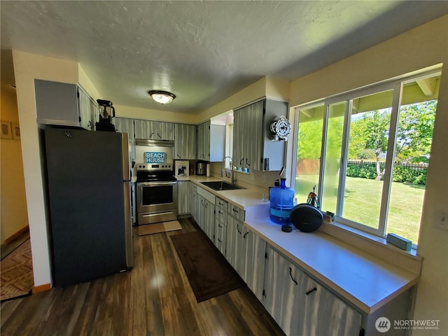 248 Ensign Ave NW, Ocean Shores, WA 98569 - kitchen featuring appliances with stainless steel finishes, a sink, light countertops, dark wood-style flooring, and under cabinet range hood