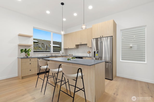 8337 14th Ave NW Unit A, Seattle, WA 98117 - kitchen featuring appliances with stainless steel finishes, light brown cabinetry, dark countertops, a kitchen breakfast bar, and a center island