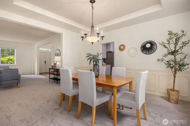 23600 Dunbar Pl NW, Poulsbo, WA 98370 - dining area with light colored carpet, a raised ceiling, crown molding, wainscoting, and a chandelier