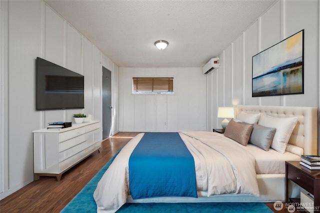 177 E St SE, Ephrata, WA 98823 - bedroom featuring dark wood-style flooring, a wall mounted air conditioner, a decorative wall, and a textured ceiling