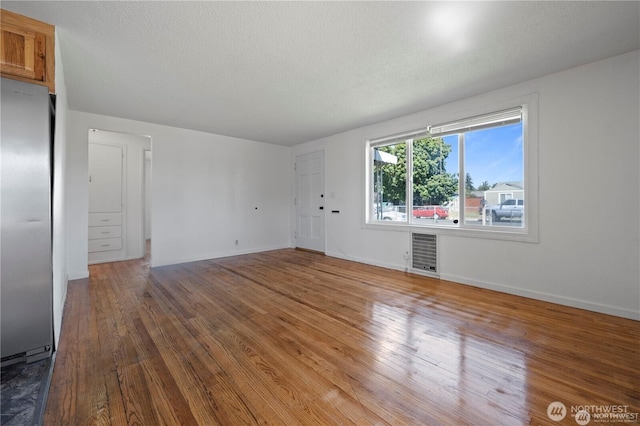 177 E St SE, Ephrata, WA 98823 - unfurnished living room featuring heating unit, wood finished floors, baseboards, and a textured ceiling