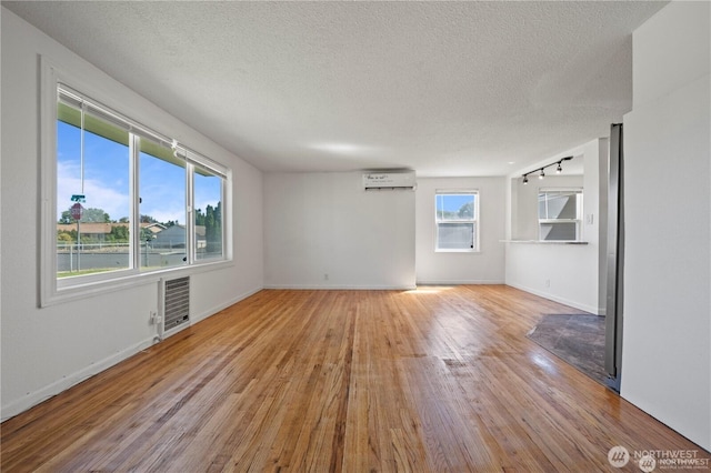 177 E St SE, Ephrata, WA 98823 - spare room with a wall unit AC, wood finished floors, baseboards, and a textured ceiling