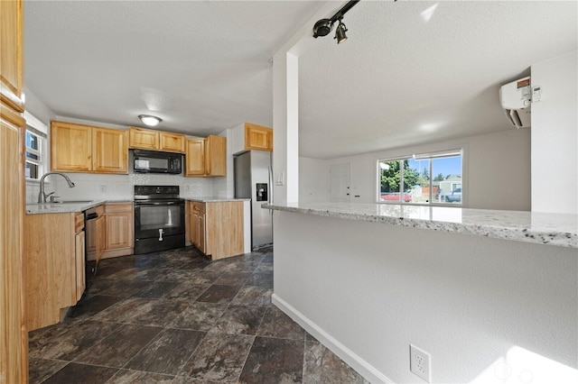 177 E St SE, Ephrata, WA 98823 - kitchen featuring black appliances, a sink, stone finish floors, an AC wall unit, and backsplash