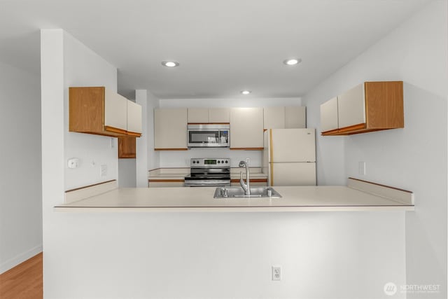 10329 Meridian Ave N Unit A201, Seattle, WA 98133 - kitchen featuring appliances with stainless steel finishes, a sink, a peninsula, recessed lighting, and light wood-style floors