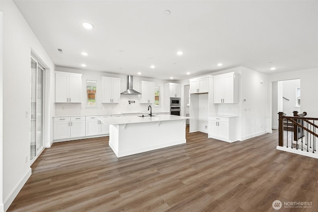 15602 210th Ave E Unit 314, Bonney Lake, WA 98391 - kitchen featuring wall chimney exhaust hood, recessed lighting, white cabinetry, a kitchen island with sink, and decorative backsplash