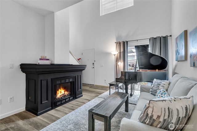 14525 1st Ln NE Unit C, Duvall, WA 98019 - living room featuring light wood-type flooring, a high ceiling, a glass covered fireplace, and baseboards