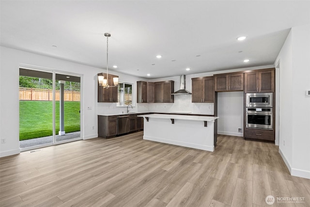 15612 210th Ave E Unit 313, Bonney Lake, WA 98391 - kitchen featuring wall chimney range hood, appliances with stainless steel finishes, light wood-style floors, light countertops, and dark brown cabinetry