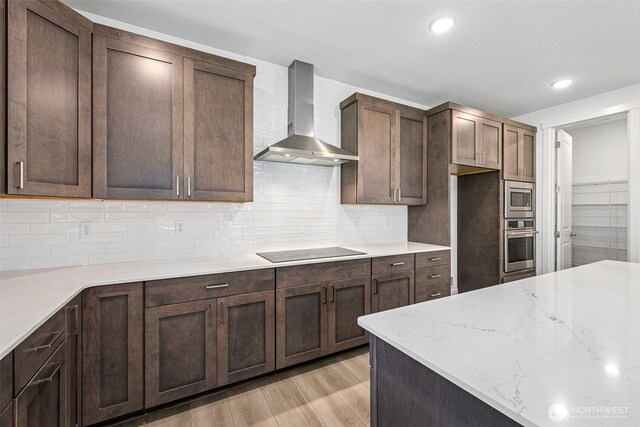 15612 210th Ave E Unit 313, Bonney Lake, WA 98391 - kitchen featuring wall chimney exhaust hood, appliances with stainless steel finishes, light wood-style floors, tasteful backsplash, and recessed lighting