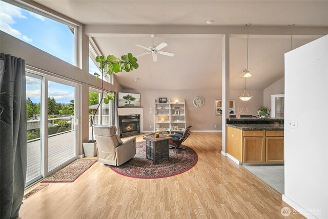 1402 E Lake Dr, Bremerton, WA 98312 - living area featuring light wood finished floors, a glass covered fireplace, high vaulted ceiling, beam ceiling, and baseboards