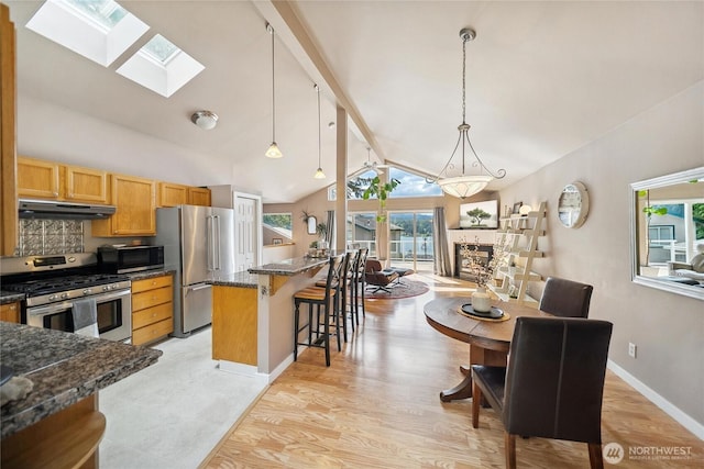 1402 E Lake Dr, Bremerton, WA 98312 - kitchen featuring appliances with stainless steel finishes, under cabinet range hood, a kitchen breakfast bar, a skylight, and light wood-style flooring