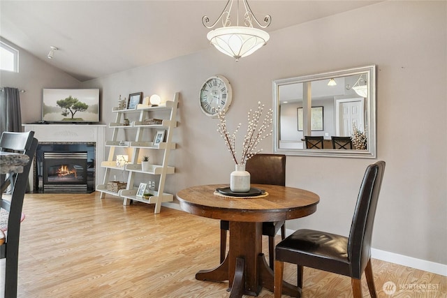 1402 E Lake Dr, Bremerton, WA 98312 - dining room with wood finished floors, vaulted ceiling, a glass covered fireplace, and baseboards