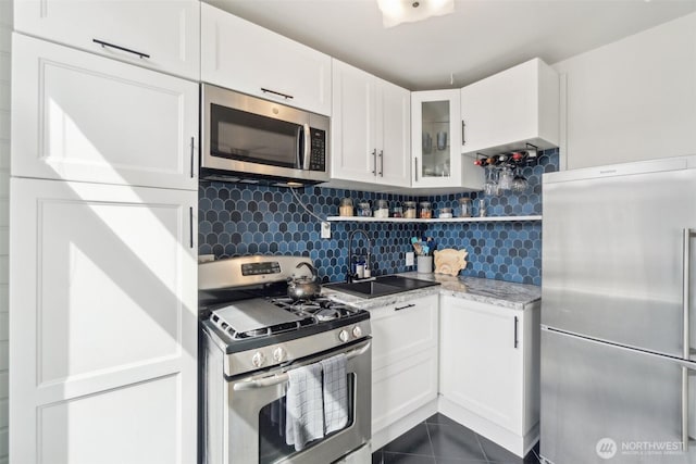 22 John St Unit 10, Seattle, WA 98109 - kitchen with stainless steel appliances, white cabinetry, decorative backsplash, and glass insert cabinets
