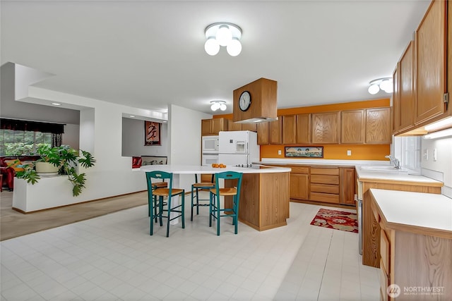 4716 266th St E, Spanaway, WA 98387 - kitchen with a breakfast bar area, white appliances, a kitchen island, a sink, and light countertops