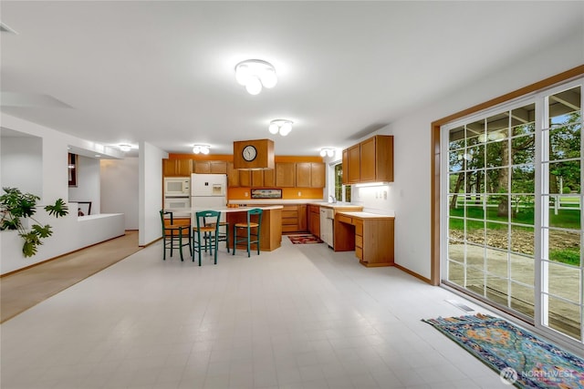 4716 266th St E, Spanaway, WA 98387 - kitchen featuring white appliances, a breakfast bar area, light countertops, a sink, and brown cabinets