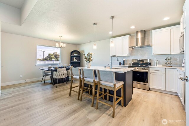 4208 W Sandy Ct, Moses Lake, WA 98837 - kitchen with stainless steel appliances, wall chimney range hood, a center island with sink, tasteful backsplash, and light wood-style floors