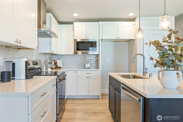 4208 W Sandy Ct, Moses Lake, WA 98837 - kitchen featuring appliances with stainless steel finishes, wall chimney exhaust hood, white cabinetry, recessed lighting, and light wood-type flooring
