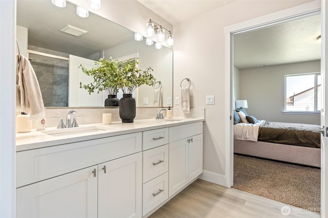 4208 W Sandy Ct, Moses Lake, WA 98837 - ensuite bathroom with double vanity, wood finished floors, a tile shower, and tasteful backsplash