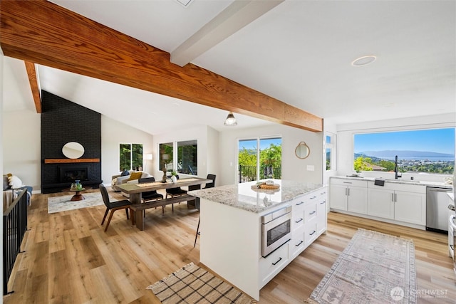3020 Alpine Dr, Bellingham, WA 98226 - kitchen with stainless steel appliances, a sink, open floor plan, white cabinets, and a fireplace