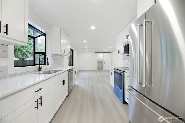 9828 33rd Dr SE, Everett, WA 98208 - kitchen with stainless steel appliances, light wood-style flooring, tasteful backsplash, a sink, and white cabinetry