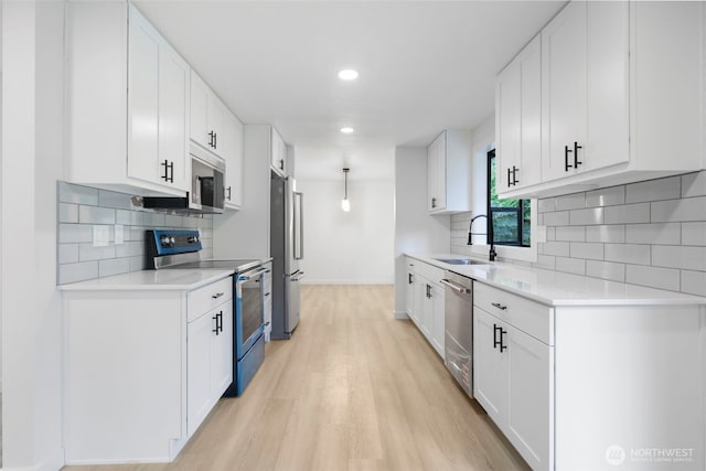 9828 33rd Dr SE, Everett, WA 98208 - kitchen with stainless steel appliances, a sink, light wood-style floors, light countertops, and baseboards